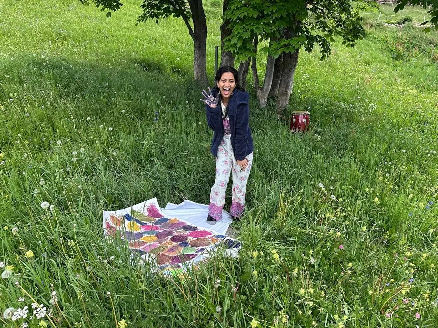 Ritty waving beside a painting laid out on the grass