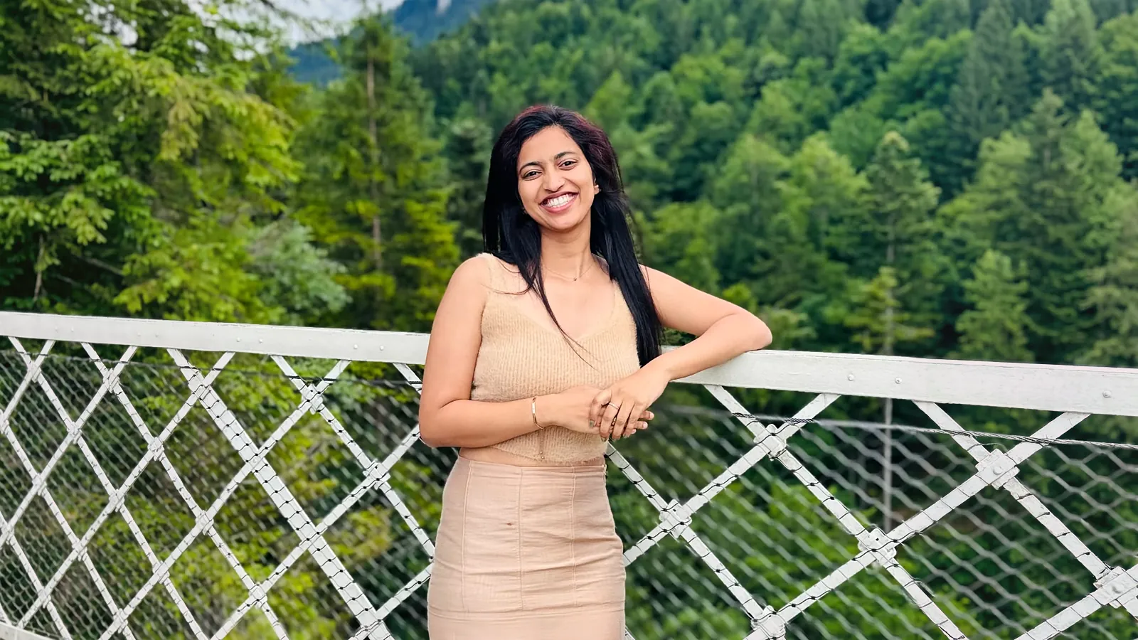 Ritty Thomas on a bridge in the forest, smiling