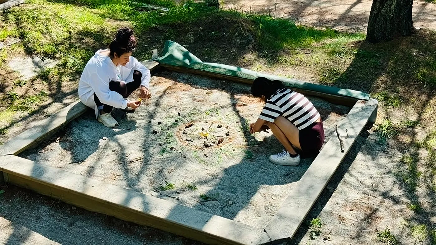 Two people creating a mandala in a sand pit