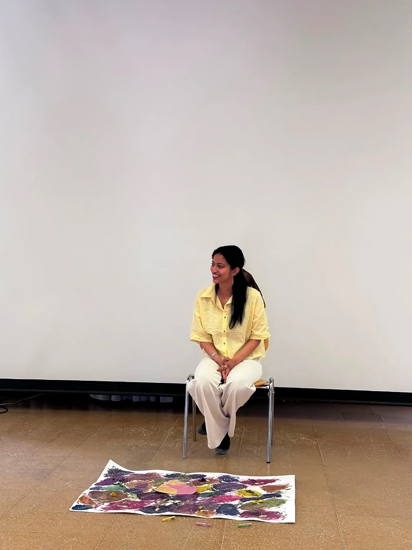 Ritty sitting in a studio with a large painting on the floor